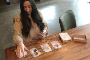 Washougal resident Taylor Eaton demonstrates how to use "The Wealthy Woman Oracle Deck" at Washougal Coffee Company on Tuesday, Dec. 13. (Doug Flanagan/Post-Record)