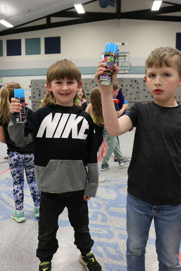 Gause Elementary School students Titus Mitchell (left) and Kylen Elkins shake spray cans before covering their physical education teacher, Mark Bauer (not pictured), with "silly string" on Tuesday, March 28, 2023. (Contributed photo courtesy of the Washougal School District)