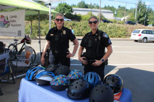 Camas Police Chief Tina Jones (left) and her officers hand out free helmets  Thursday, July 27, 2023, during a grand reopening event for Camas' Riverside Bowl Skatepark. (Kelly Moyer/Post-Record files) 