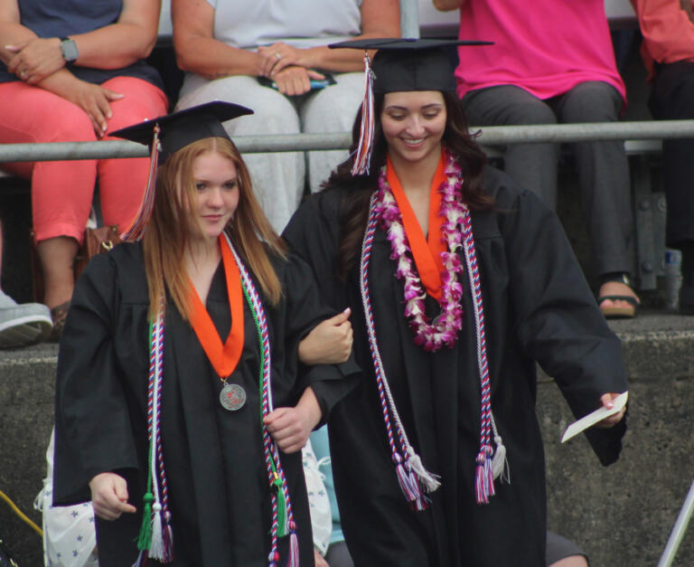 A pair of Washougal High School graduates walk to their seats at the start of the the school&rsquo;s Class of 2024 graduation ceremony on June 8, 2024, at Fishback Stadium.