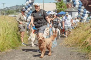 Washougal Police Chief Wendi Steinbronn walks a dog during the West Columbia Gorge Humane Society’s Hike on the Dike fundraising event, June 25, 2022. (Contributed photo courtesy of West Columbia Gorge Humane Society)