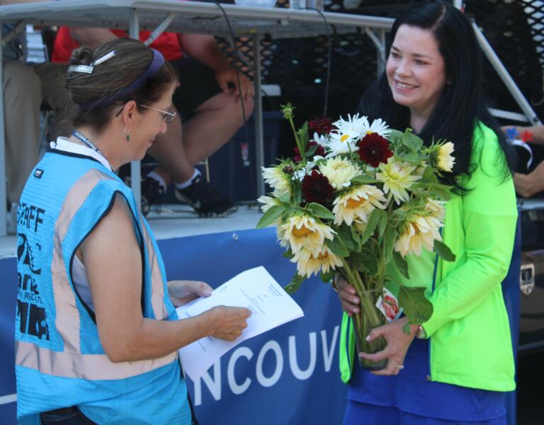 Camas-Washougal Chamber of Commerce Director Jennifer Senescu (right) presents a bouquet of flowers to Camas Recreation Coordinator Krista Bashaw, thanking her for her years' of service coordinating the Kids Parade during the annual Camas Days festival, Friday, July 26, 2024. (Kelly Moyer/Post-Record) 