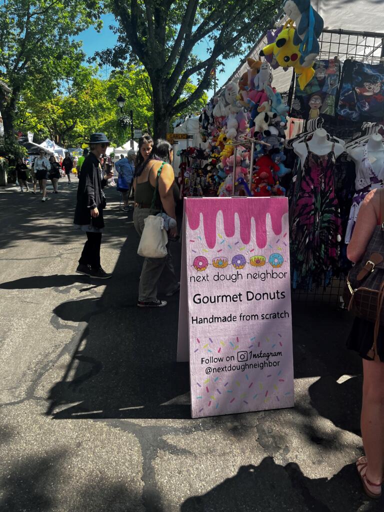 A sign points to Next Dough Neighbor in downtown Camas during the 2024 Camas Days festival, Friday, July 26, 2024. (Kelly Moyer/Post-Record) 