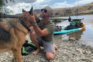 Michael Curtis, of Washougal, greets a dog along the Columbia River, in 2024. Curtis has raised more than $56,000 for Northwest Battle Buddies through his 1,000-mile journey down the Columbia River on a stand-up paddleboard. . (Contributed photos courtesy of Michael Curtis)