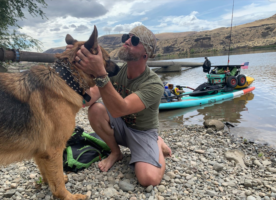 Michael Curtis, of Washougal, greets a dog along the Columbia River, in 2024. Curtis has raised more than $56,000 for Northwest Battle Buddies through his 1,000-mile journey down the Columbia River on a stand-up paddleboard. . (Contributed photos courtesy of Michael Curtis)