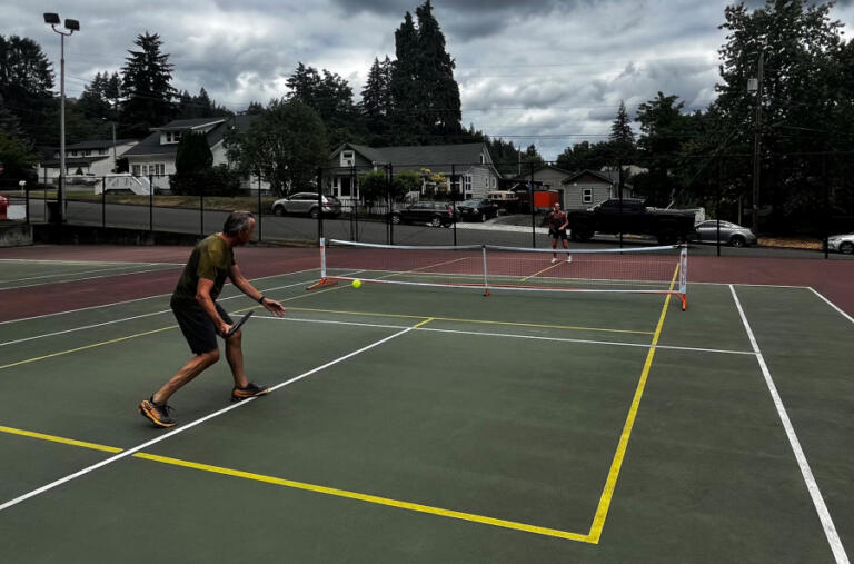 Camas residents Dawn (left) and John Hendricks set up a pickleball net, Monday, Aug. 12, 2024, at the shared-use tennis-pickleball courts at Crown Park in Camas. The Hendricks, who have been playing pickleball since their daughter introduced them to the sport last year, say they have not had any conflicts over the city of Camas' shared-use schedule at Crown Park.