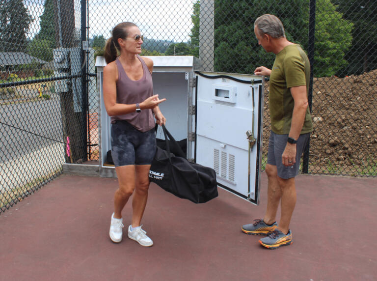 Camas residents Dawn (left) and John Hendricks retrieve a pickleball net from a shared-use locker at the Crown Park tennis-pickleball courts, Monday, Aug. 12, 2024.