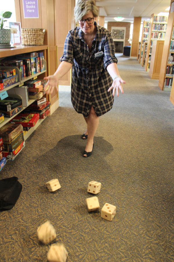 Camas Public Library Director Connie Urquhart demonstrates how to play “Yardzee,” one of the library’s Nature Smart games, Thursday, Aug. 15, 2024, inside the Camas library. (Photos by Kelly Moyer/Post-Record)