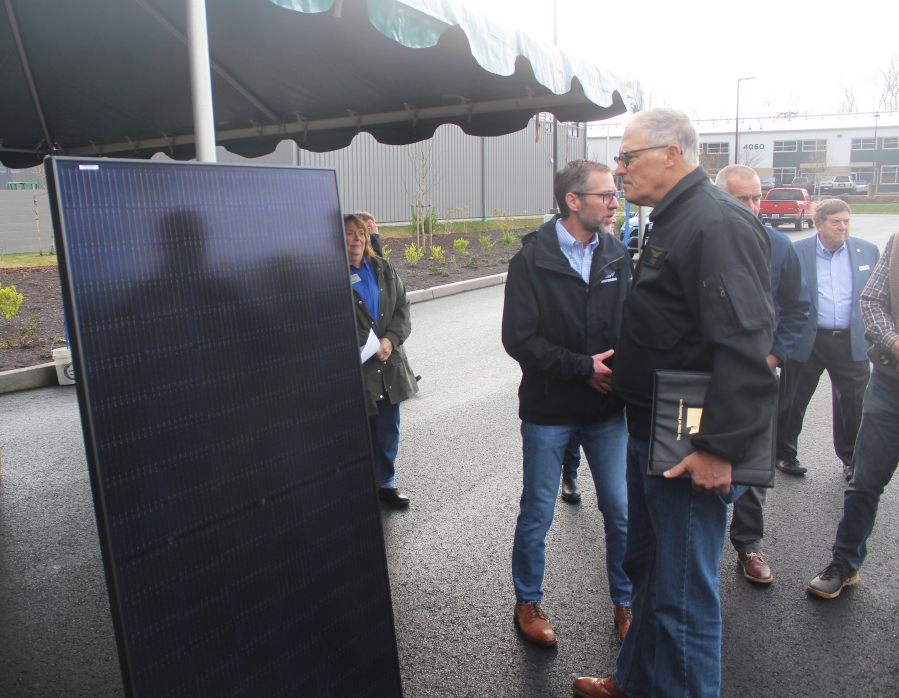 Washington Gov. Jay Inslee (center) inspects a solar panel used in Clark Public Utilities’ Community Solar East project at the Port of Camas-Washougal’s industrial park in Washougal, Friday, Jan. 5, 2024. (Doug Flanagan/Post-Record)