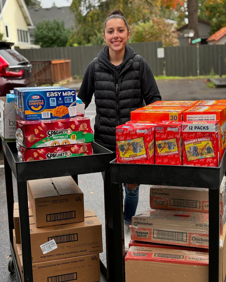 Sadie Armstrong, an employee of Triple C Auto in Washougal, stands next to boxes of food to be donated to the East County Family Resource Center in October 2024.