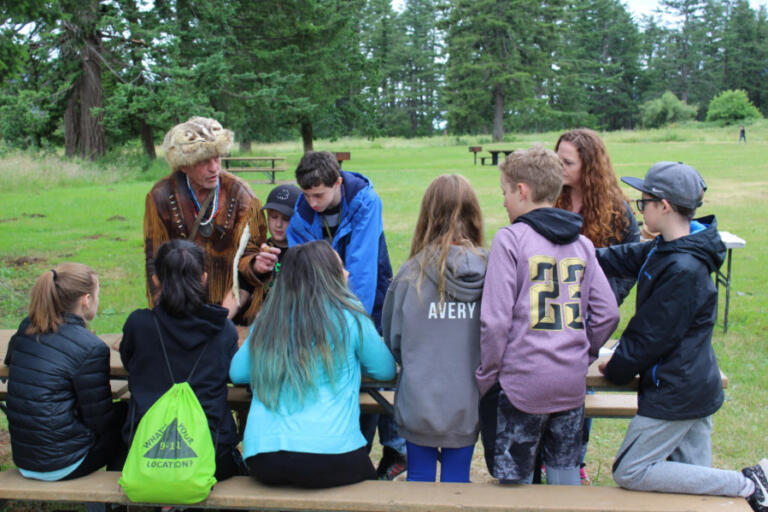 Washougal sixth grade students from Canyon Creek Middle School listen to historian and Lewis and Clark expert Roger Wendlick (back, left) discuss the various tools used by the Corps of Discovery during their journey toward the Pacific Ocean in the early 1800s at an outdoor school held June 14, 2018, during a Friends of the Columbia Gorge outdoor environmental education program funded by a Camas-Washougal Community Chest grant.