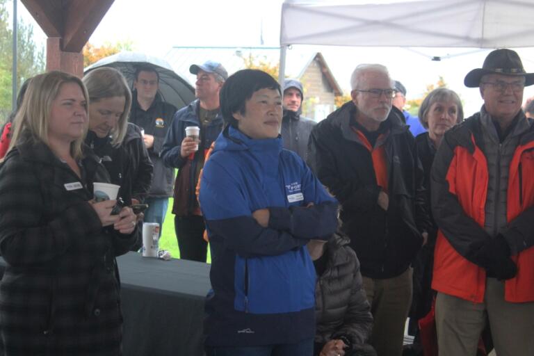 Port of Camas-Washougal Chief Executive Officer Trang Lam (center, in blue) listens to a speech during a groundbreaking ceremony for the Hyas Point development project at Washougal Waterfront Park, Thursday, Oct.